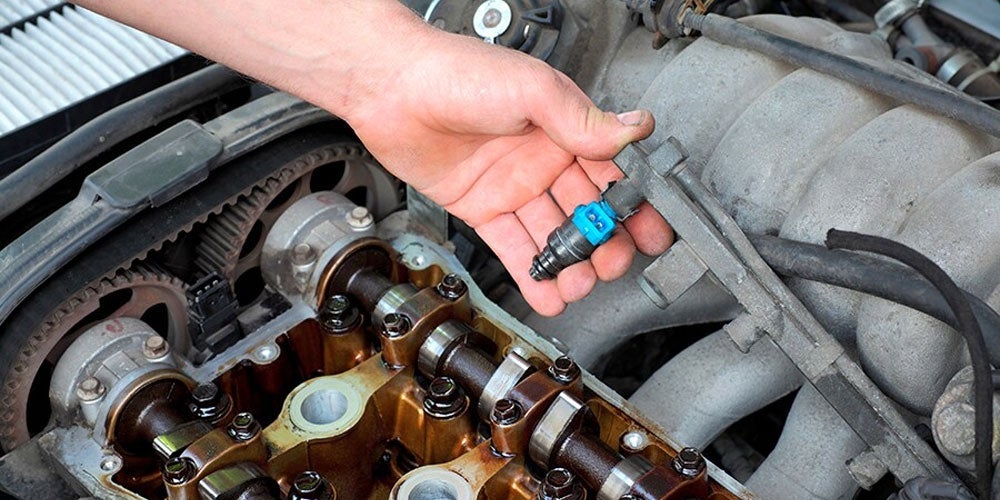 Technician examining a vehicle fuel injector